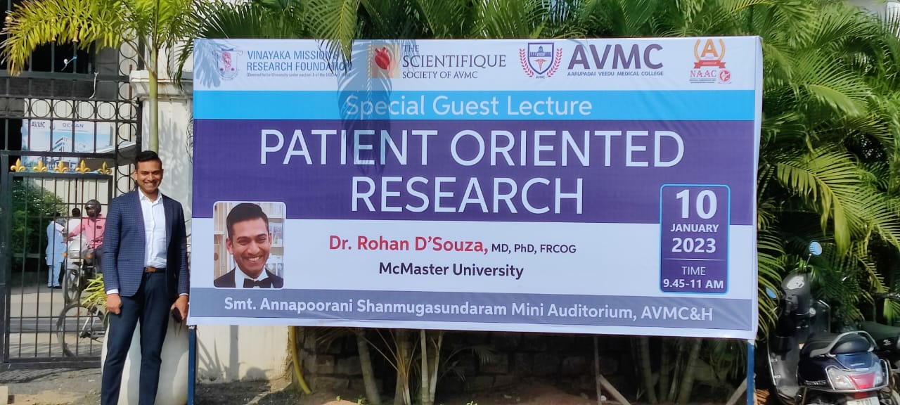 Rohan D'Souza stands next to banner advertising his talk.