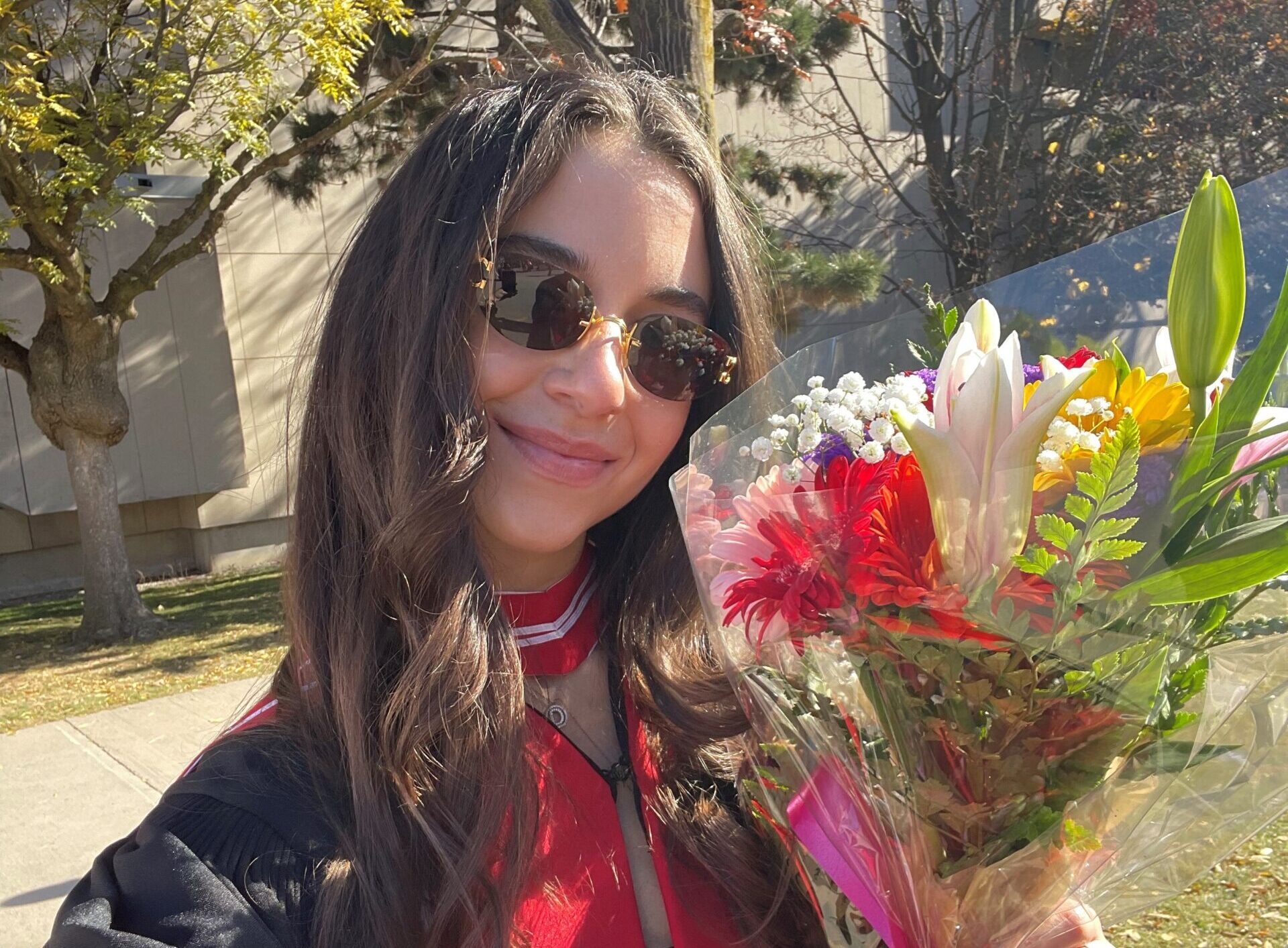 Dylan Herman wearing graduation gown and holding flowers.