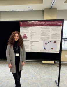 Emma Wooley standing beside her poster presented at the conference 